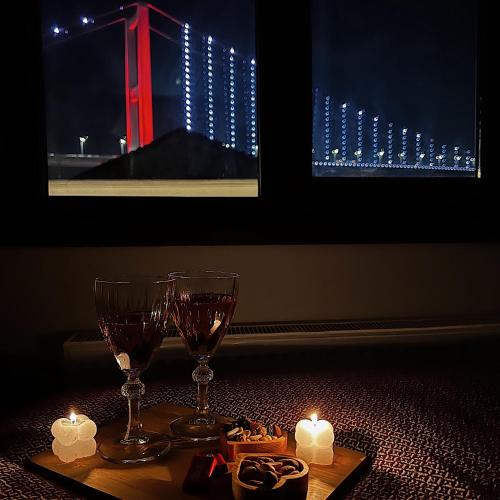 two wine glasses and candles on a table with lights at Triplex house with Bridge view in Istanbul
