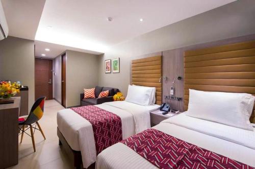 a hotel room with two beds and a desk at Solace Hotel in Manila