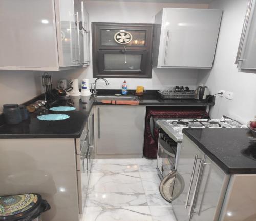 uma cozinha com armários brancos e bancadas pretas em شاليهات فندقيه منتجع Porto said em Port Said