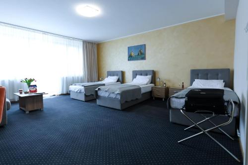 a hotel room with two beds and a chair at Smeštaj Tank, Pančevo in Salaši