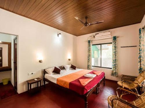 a bedroom with a bed and a chair and a window at Marari Charlys Homestay in Mararikulam