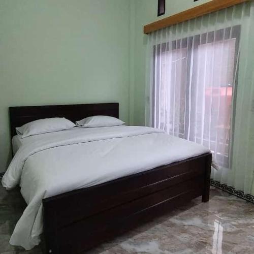 a large bed in a bedroom with a window at GUEST Toraja Homestay in Rantepao