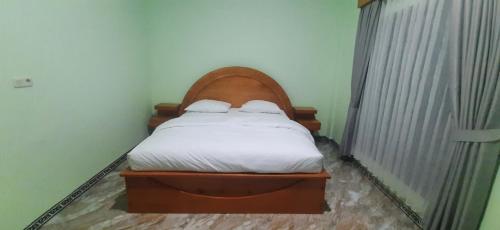 a small bedroom with a bed with white sheets at GUEST Toraja Homestay in Rantepao