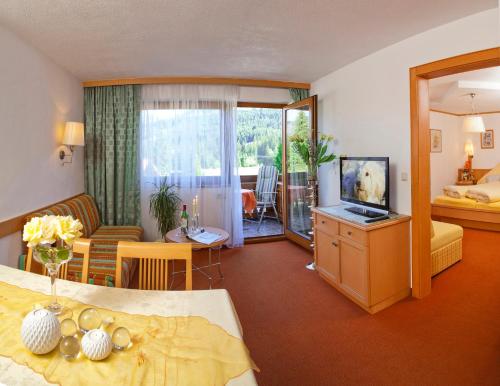 Habitación de hotel con cama y sala de estar. en Landhaus Aggenstein, en Haldensee