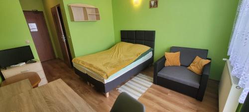 een kleine slaapkamer met een bed en een stoel bij Willa Monika in Muszyna