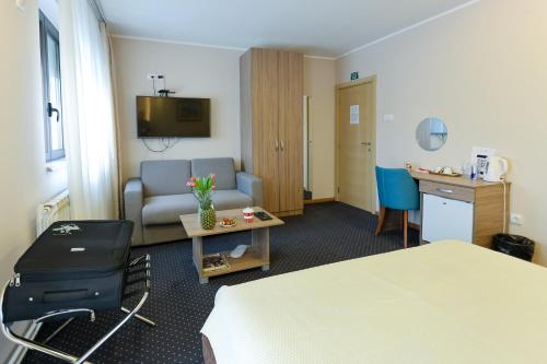 a hotel room with a bed and a couch and a table at Smeštaj Tank, Pančevo in Salaši