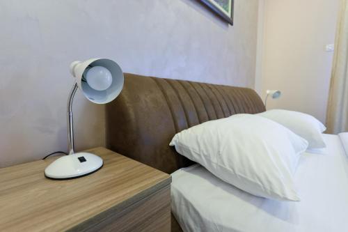 a bedroom with a bed with a lamp on a wooden table at Smeštaj Tank, Pančevo in Salaši