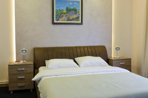 a bedroom with a bed with two nightstands and a painting at Smeštaj Tank, Pančevo in Salaši