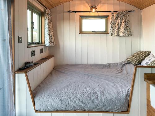 a bed in a tiny house with a window at The Hut in Langstone
