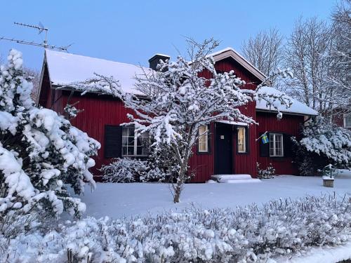 une grange rouge recouverte de neige avec une cour dans l'établissement Lilla Röda Huset., à Sjötofta