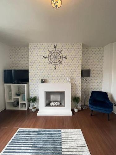 a living room with a fireplace with a clock on the wall at Beachfront Treasure in Musselburgh