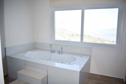 a white bathroom with a sink and a window at The Three Graces - Apollon in Antimácheia