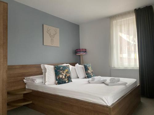 a bedroom with a bed with white sheets and a window at Pensiunea Ioana in Rugineşti