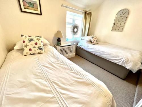 a bedroom with two beds and a window at Anchor Cottage - beautiful two bedroom cottage in the heart of Holt in Holt