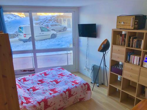 a bedroom with a bed and a window with a car outside at Studio au pied des pistes in Villard-de-Lans