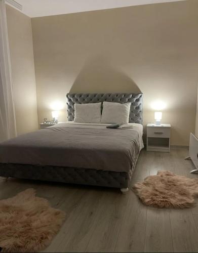 a bedroom with a large bed and two rugs at Apartman Smile in Čačak