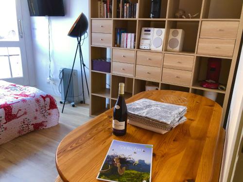 a table with a bottle of wine and a book at Studio au pied des pistes in Villard-de-Lans
