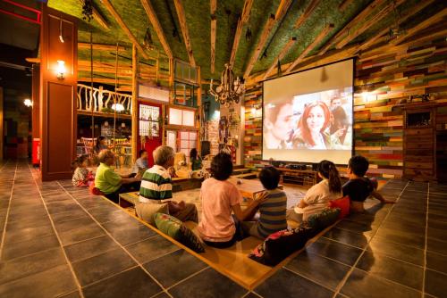 Eine Gruppe von Menschen, die auf einer Bank sitzen und einen Film auf einem Bildschirm ansehen in der Unterkunft Fly Inn 飛旅宿 in Dongshan