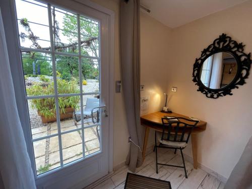 a room with a table and a mirror and a window at chambres d hotes Le Mas Julien piscine chauffée adult only in Orange