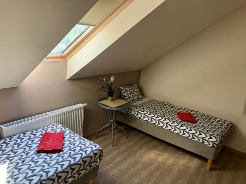 a room with a bed and a table with red pillows at Mandula Apartman in Cegléd