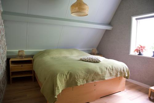 een slaapkamer met een bed met een groen dekbed en een raam bij Theetuin en B & B 'De Theetuin' in Wijckel