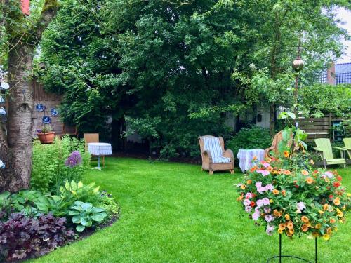 a garden with chairs and flowers on the grass at Theetuin en B & B 'De Theetuin' in Wijckel