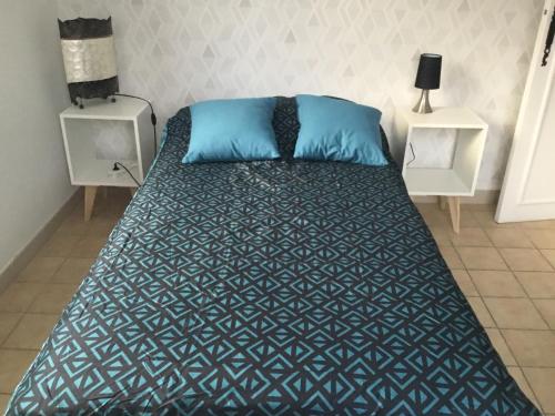 Bett mit blauen Kissen in einem Zimmer in der Unterkunft L olivier in Prades