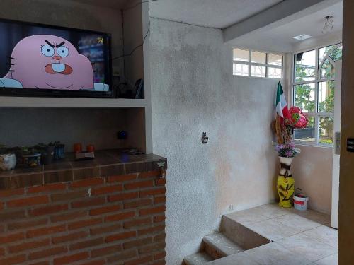 uma sala de estar com uma televisão e uma parede de tijolos em Hospedajes Tomas Wilson MX em Cidade do México