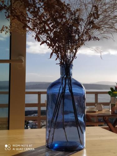 un vaso blu con dei fiori sul tavolo. di San Vicente Views a San Vicente do Mar