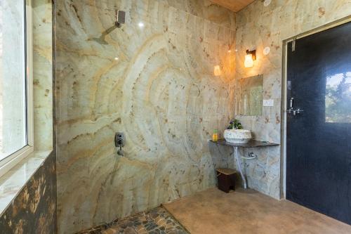 a bathroom with a stone wall with a shower at Jungle King Resort in Kānha