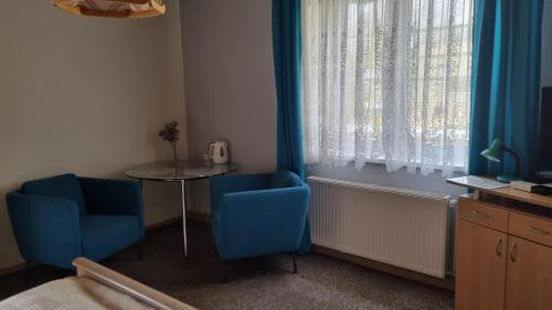 イェレニャ・グラにあるPokoje Gościnne Karinaの青い椅子2脚、テーブル、窓が備わる客室です。
