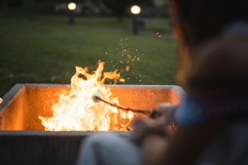 a woman is sitting in front of a fire pit at Aparthotel Familiaris - Family Apartments - Pools & Spa in Dolomites in Valdaora