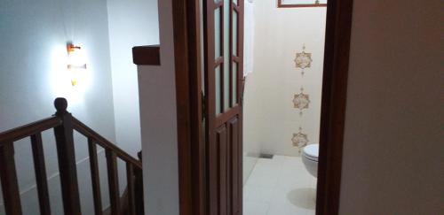 a bathroom with a toilet and a stairway with a stair railing at Sujee Villa White House in Beruwala