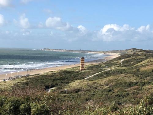 a beach with a lighthouse on a hill next to the ocean at Appartement Dishoek No.46 in Koudekerke