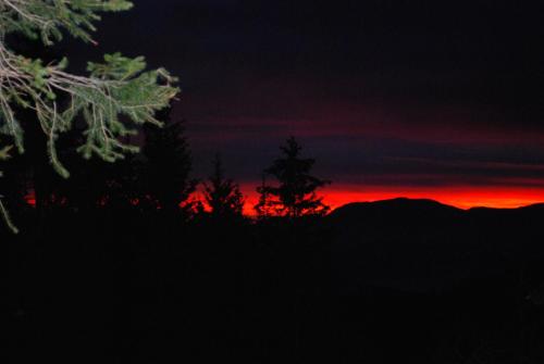 a sunset with trees and mountains in the background at Country House & Spa in Mislinja