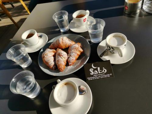 una mesa con platos de repostería y tazas de café en SaLò Apartments, en Manfredonia