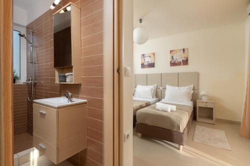 a bedroom with two beds and a bathroom with a sink at Next to Haraki beach , taverns bars & 10 to Lindos in Haraki