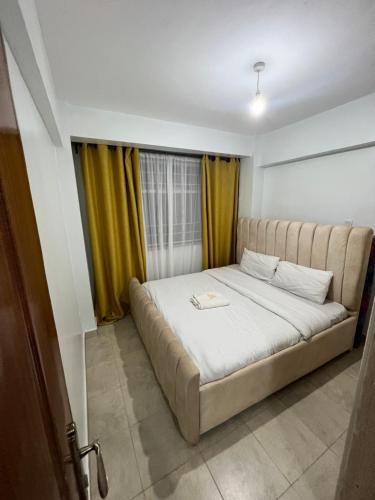 a large bed in a room with yellow curtains at Cossy homes kericho grey point in Kericho