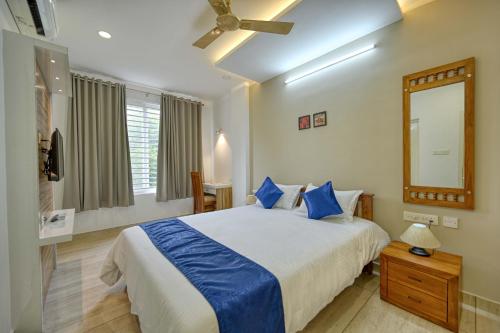 a bedroom with a bed with blue pillows and a mirror at Perumayan Arcade in Cochin