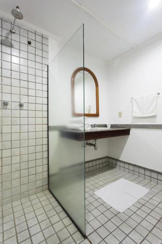 a glass shower in a bathroom with a sink at Hotel Lopes Caxambu in Caxambu