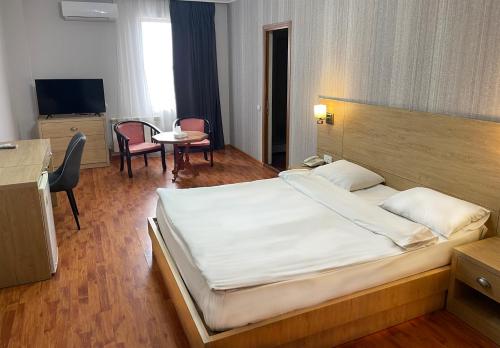 1 dormitorio con 1 cama grande, mesa y sillas en Primer Hotel, en Ereván