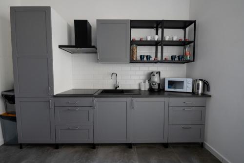 a kitchen with gray cabinets and a sink and a microwave at B&B i Murales in Naples