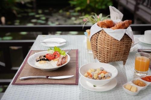 a table with two plates of food and a basket of bread at Parasol Blanc in Luang Prabang