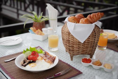 a table with plates of food and a basket of bread at Parasol Blanc in Luang Prabang