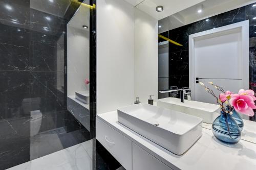 ein Badezimmer mit einem weißen Waschbecken und einem Spiegel in der Unterkunft Julia by Q4Apartments - close to the beach in Danzig