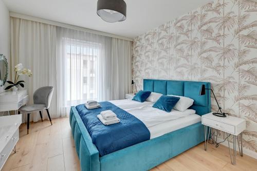 ein Schlafzimmer mit einem blauen Bett und einem Stuhl in der Unterkunft Julia by Q4Apartments - close to the beach in Danzig