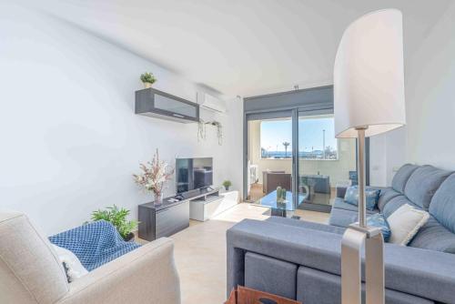 a living room with a blue couch and a tv at Goldhome - Cristallmar in Empuriabrava
