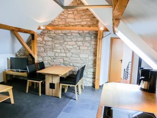 a table and chairs in a room with a stone wall at Gästezimmer im Weingut Wolf in Großkarlbach