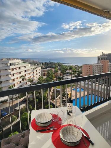 un tavolo bianco con 2 piatti e bicchieri da vino su un balcone di Appartamento vista oceano a pochi passi dal mare a Playa Fañabe