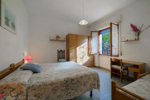 a bedroom with two beds and a desk and a window at Appartamento Pomonte la Posta - Goelba in Pomonte